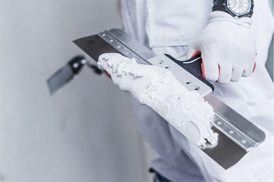 A man is holding a spatula filled with white paint.