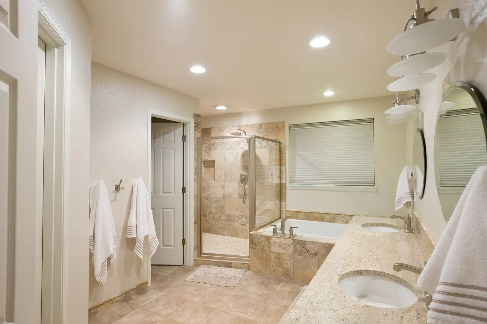 A bathroom with two sinks , a tub , a shower and a mirror.