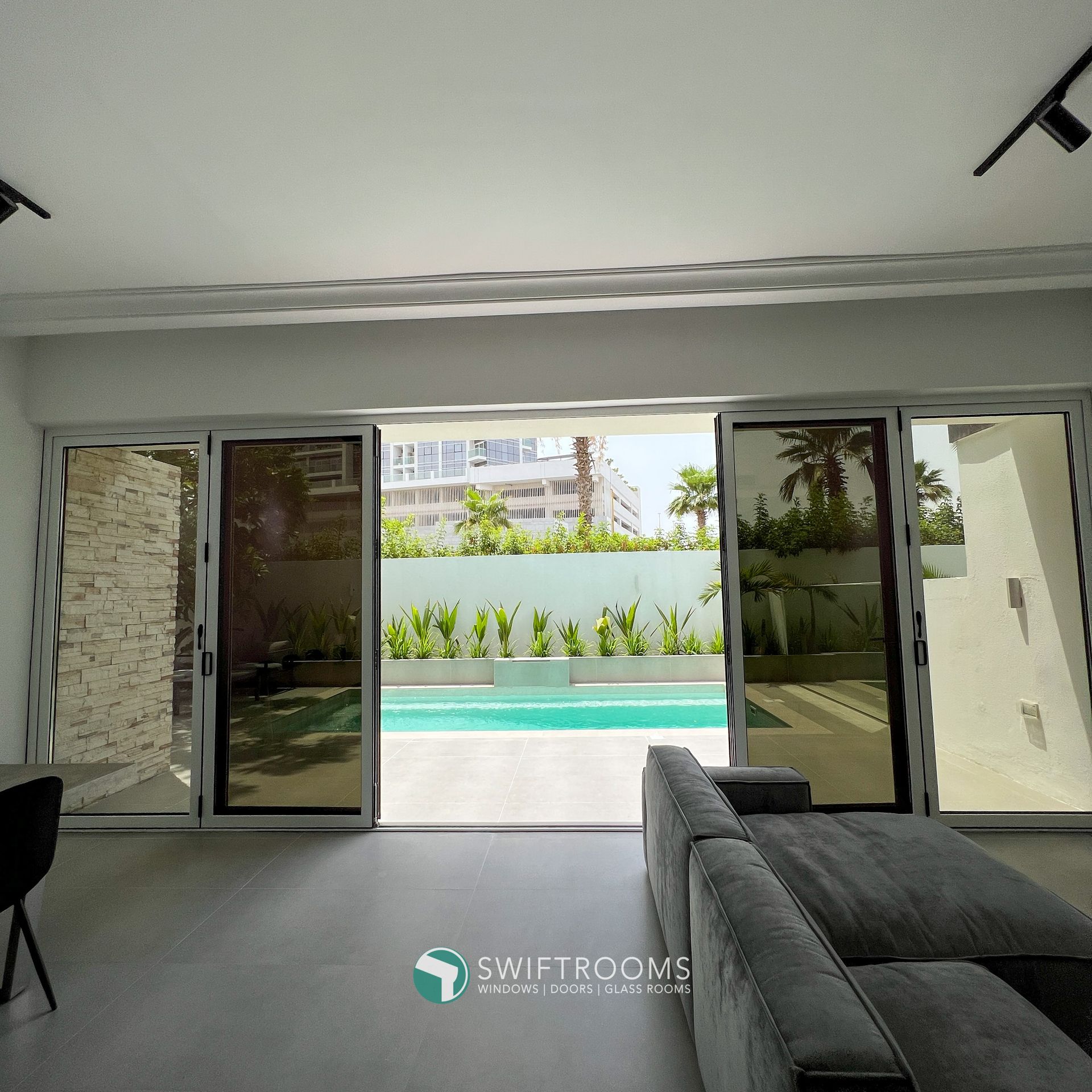 A living room with a couch and sliding glass doors leading to a swimming pool.