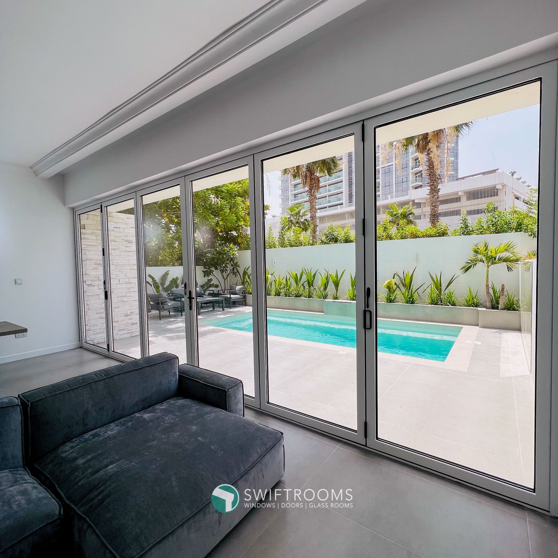 A living room with a couch and sliding glass doors leading to a pool