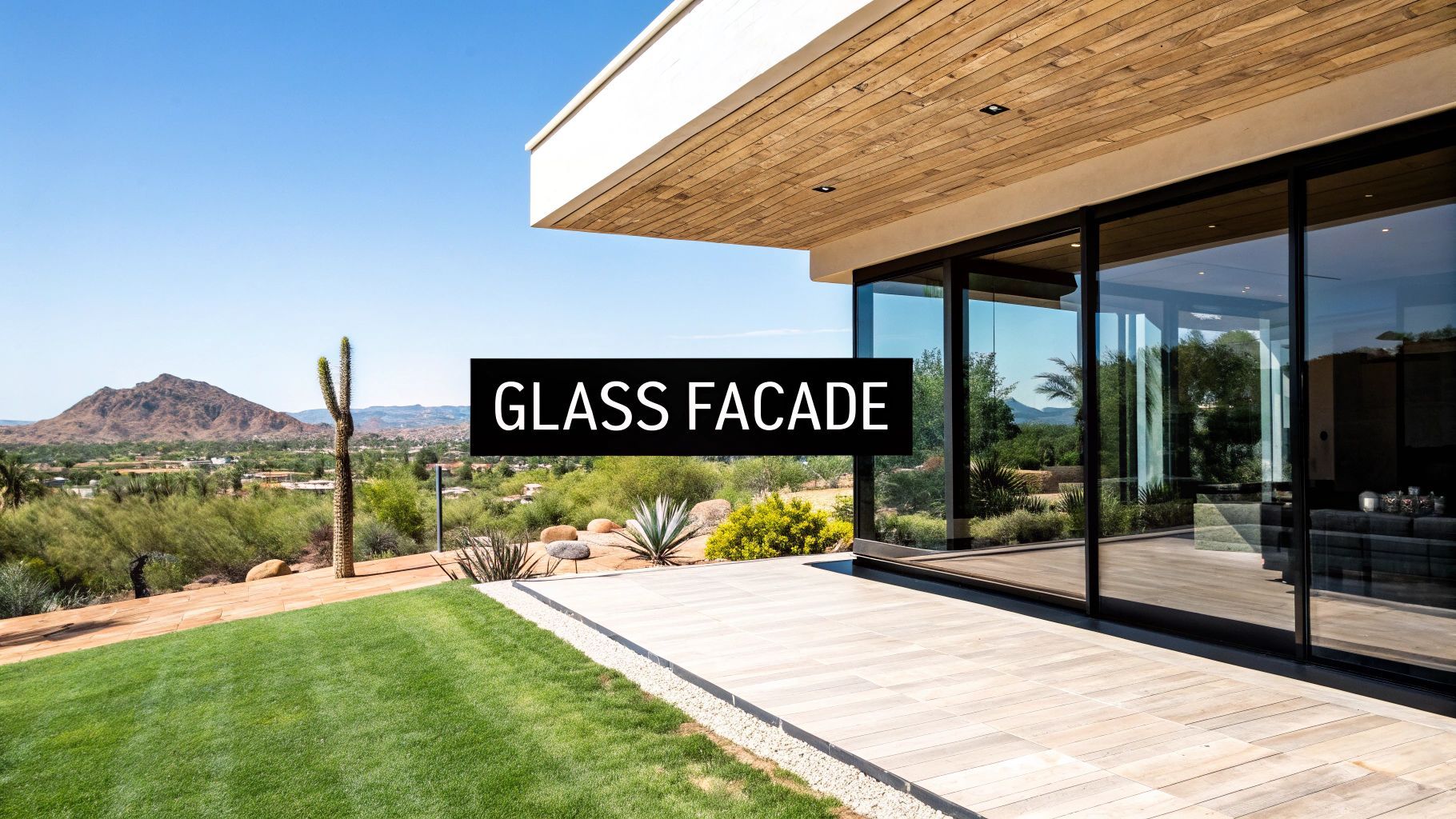 Modern home with glass facade, patio, and desert landscape view.
