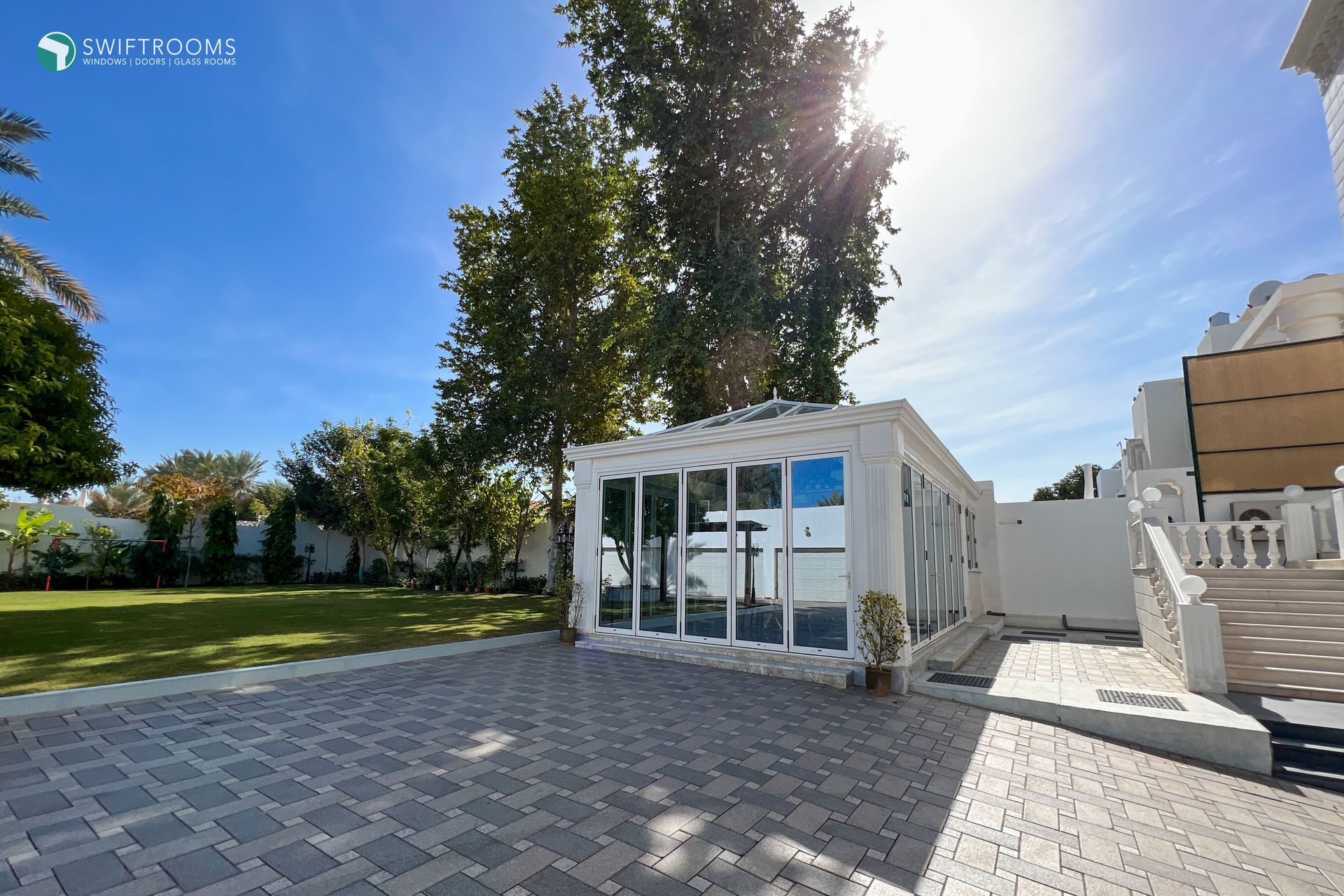 A large white building with a lot of windows is surrounded by trees.