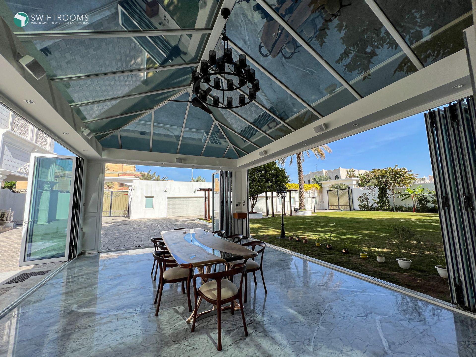 A dining room with a table and chairs under a glass roof.