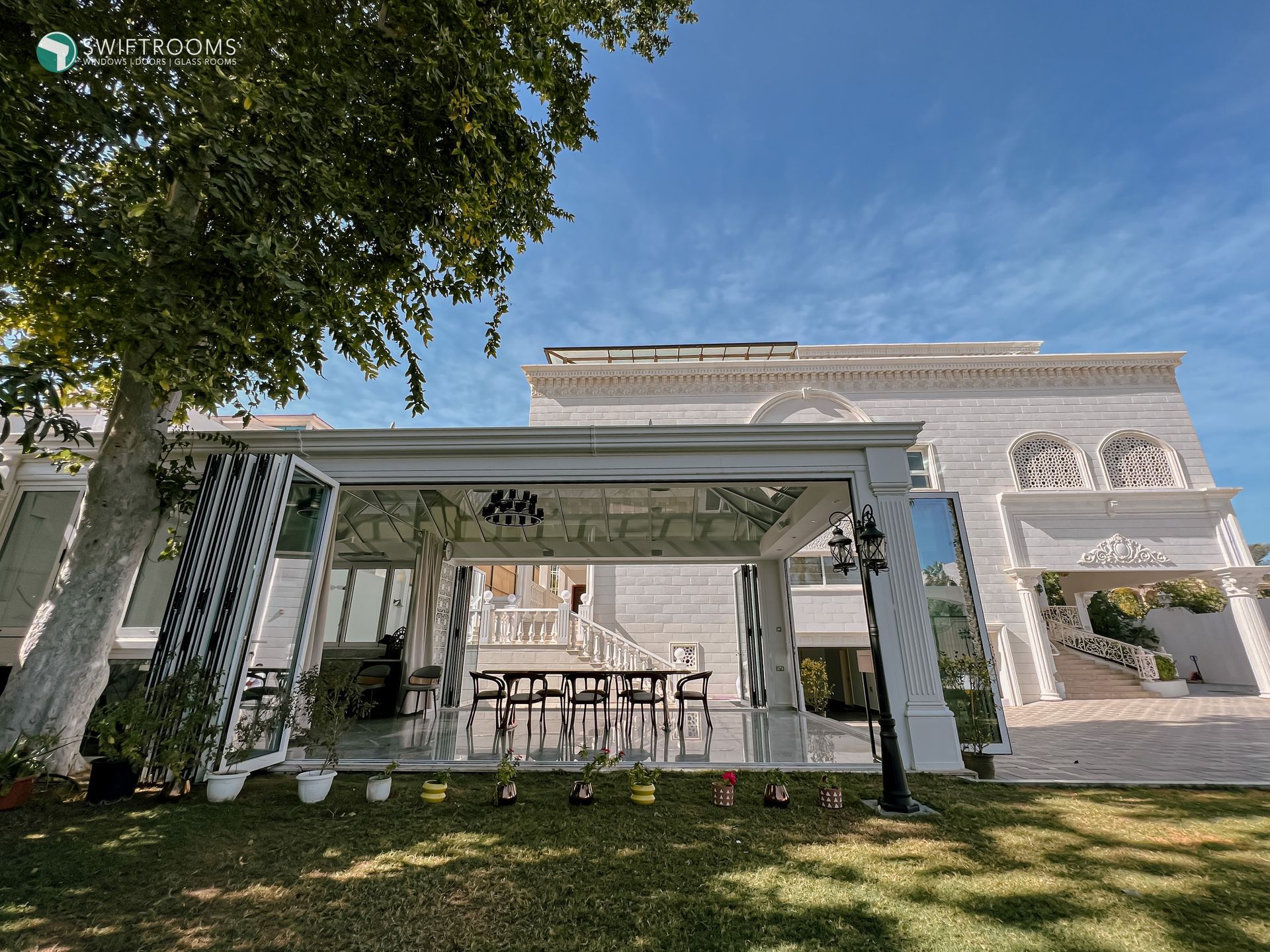 A large white house with a pergola in front of it.