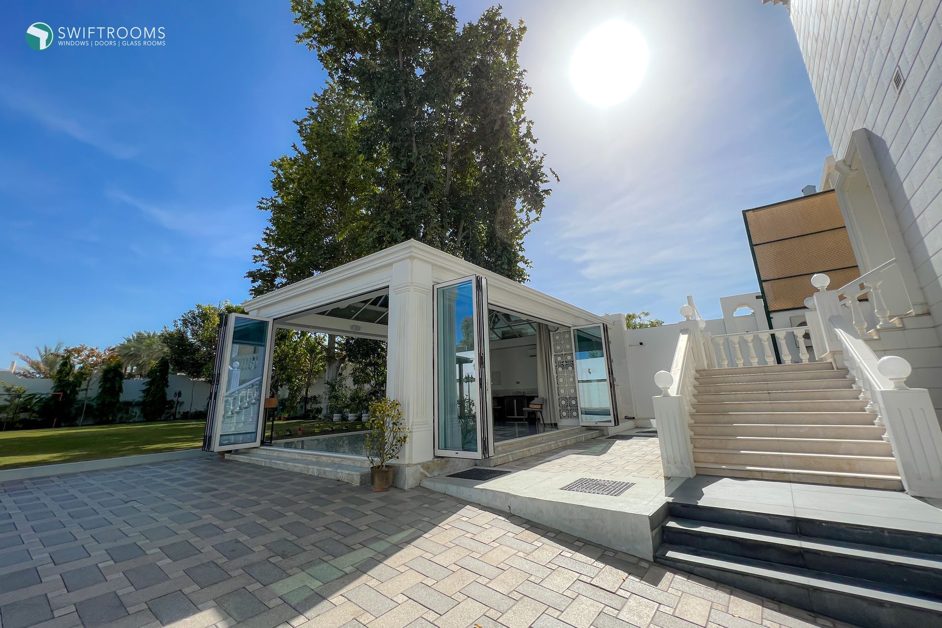 A white house with a gazebo and stairs in front of it.