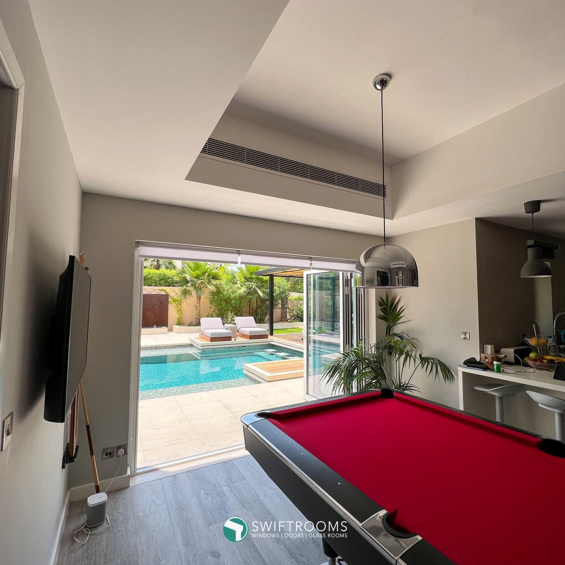 A pool table in a room with a pool in the background
