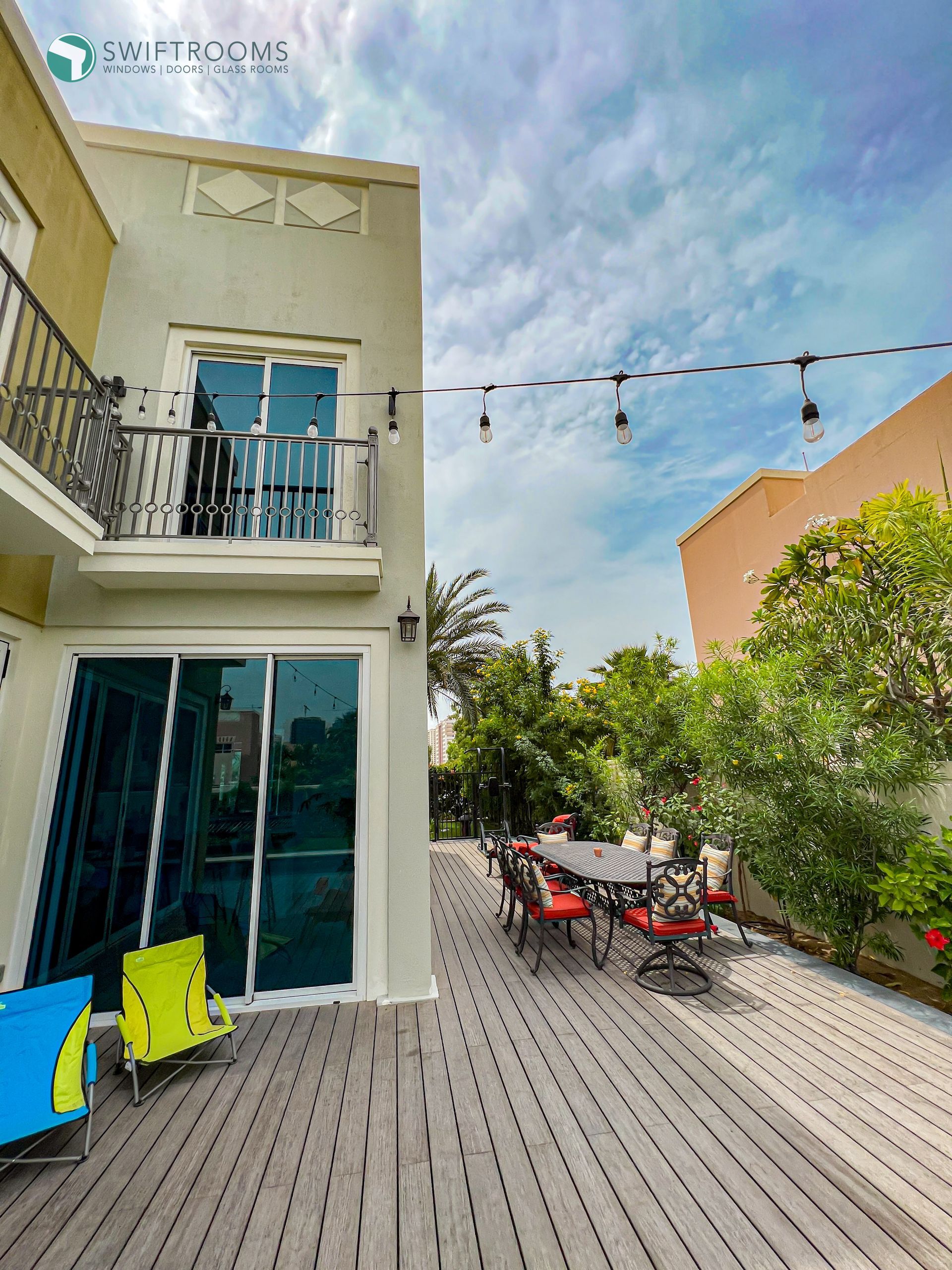 A large deck with a table and chairs in front of a house.