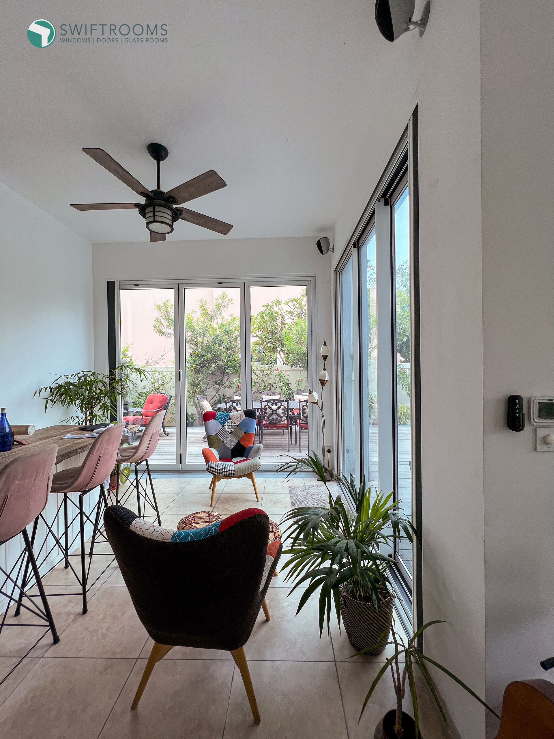A living room with a ceiling fan and lots of windows