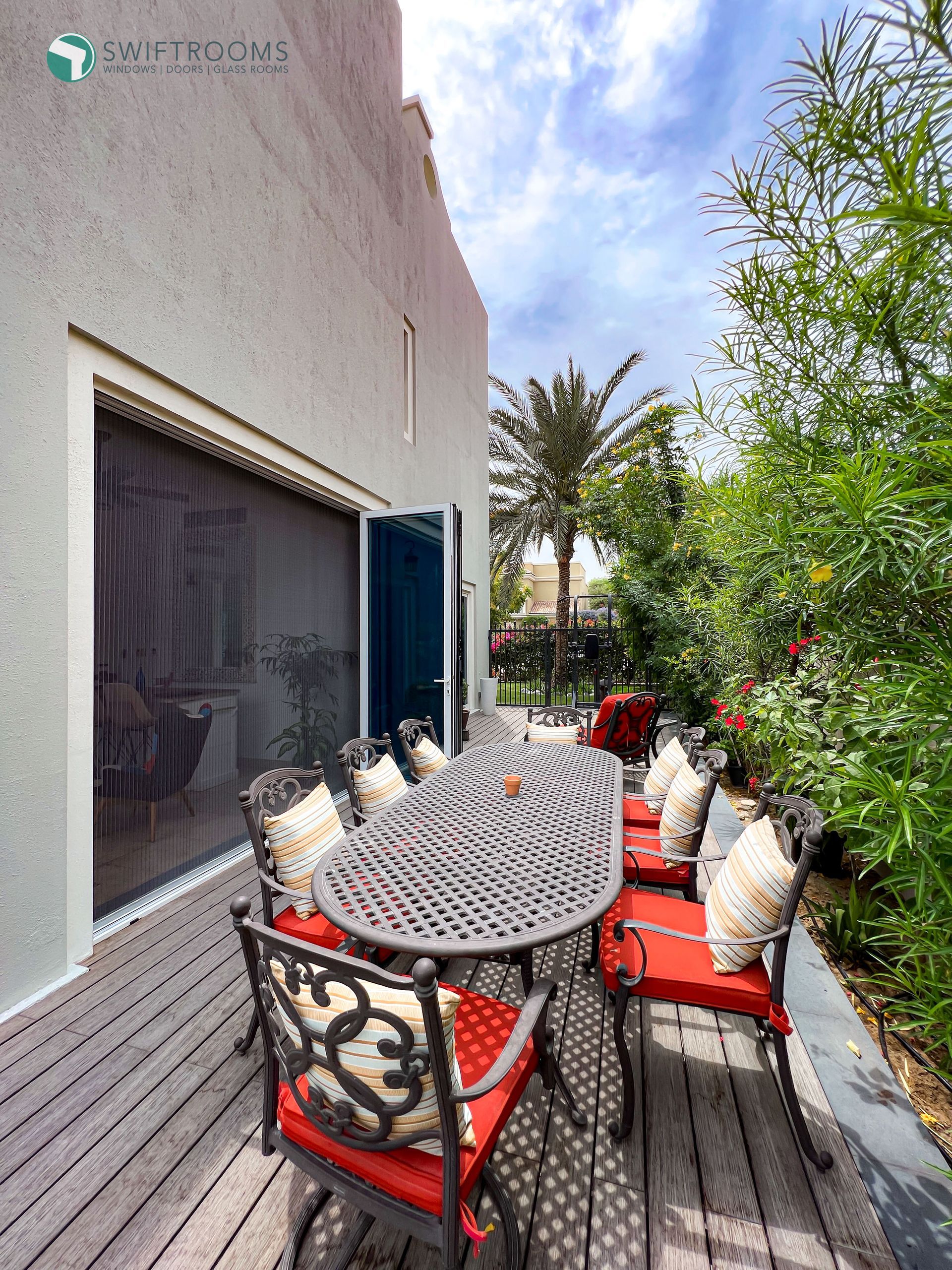 There is a table and chairs on the deck of a house.