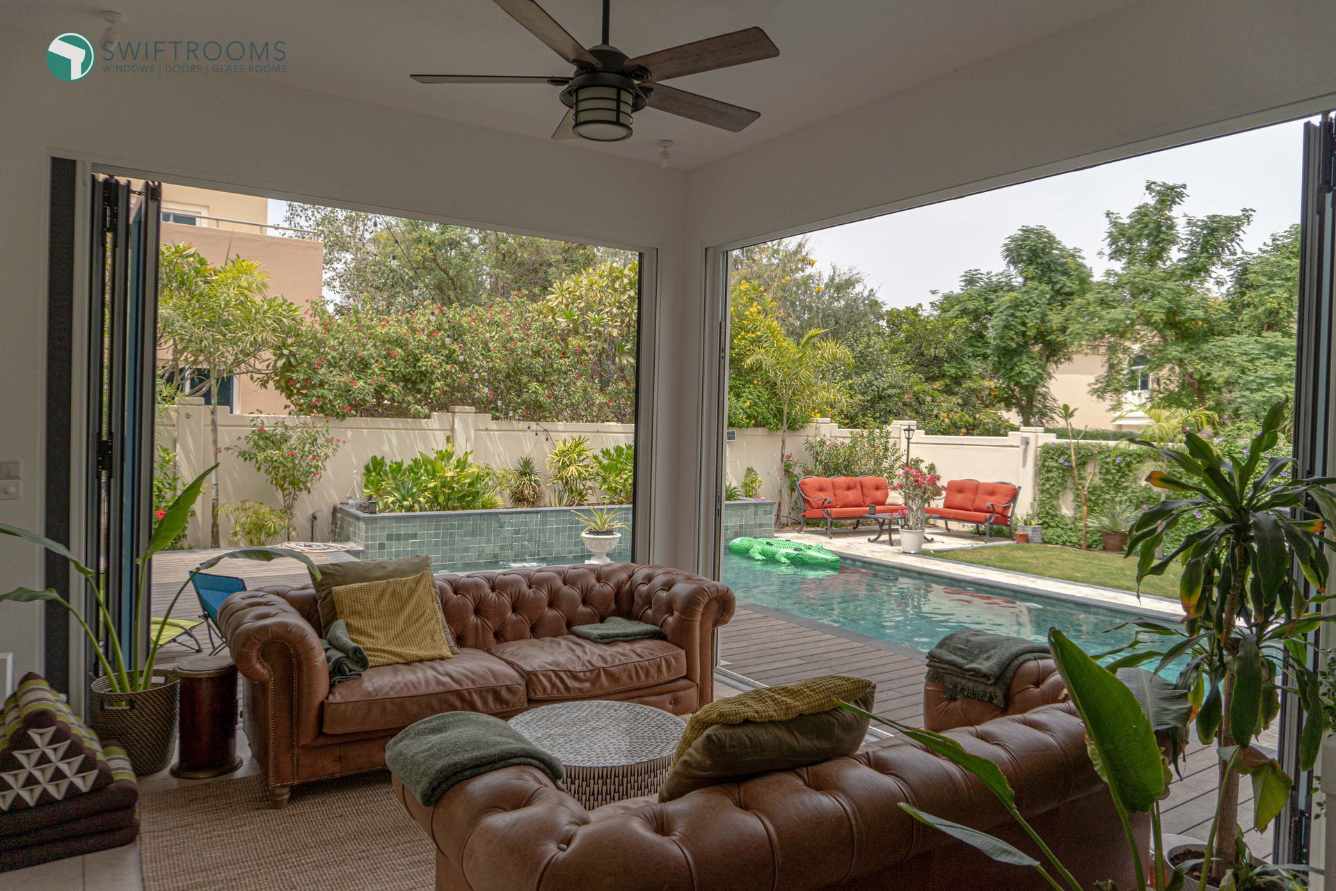 A living room with a couch , table , and ceiling fan.