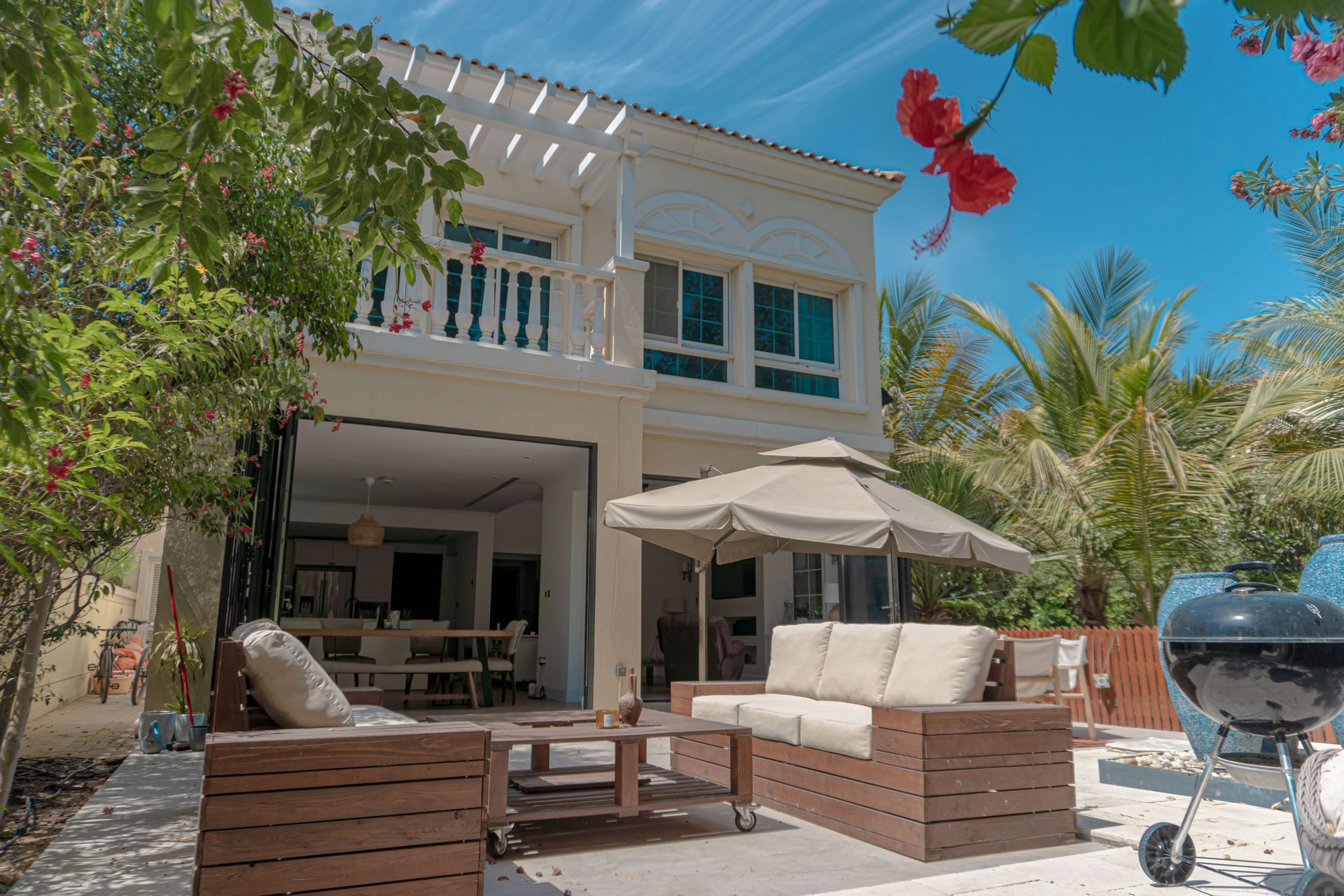 A large white house with a patio area with furniture and umbrellas.