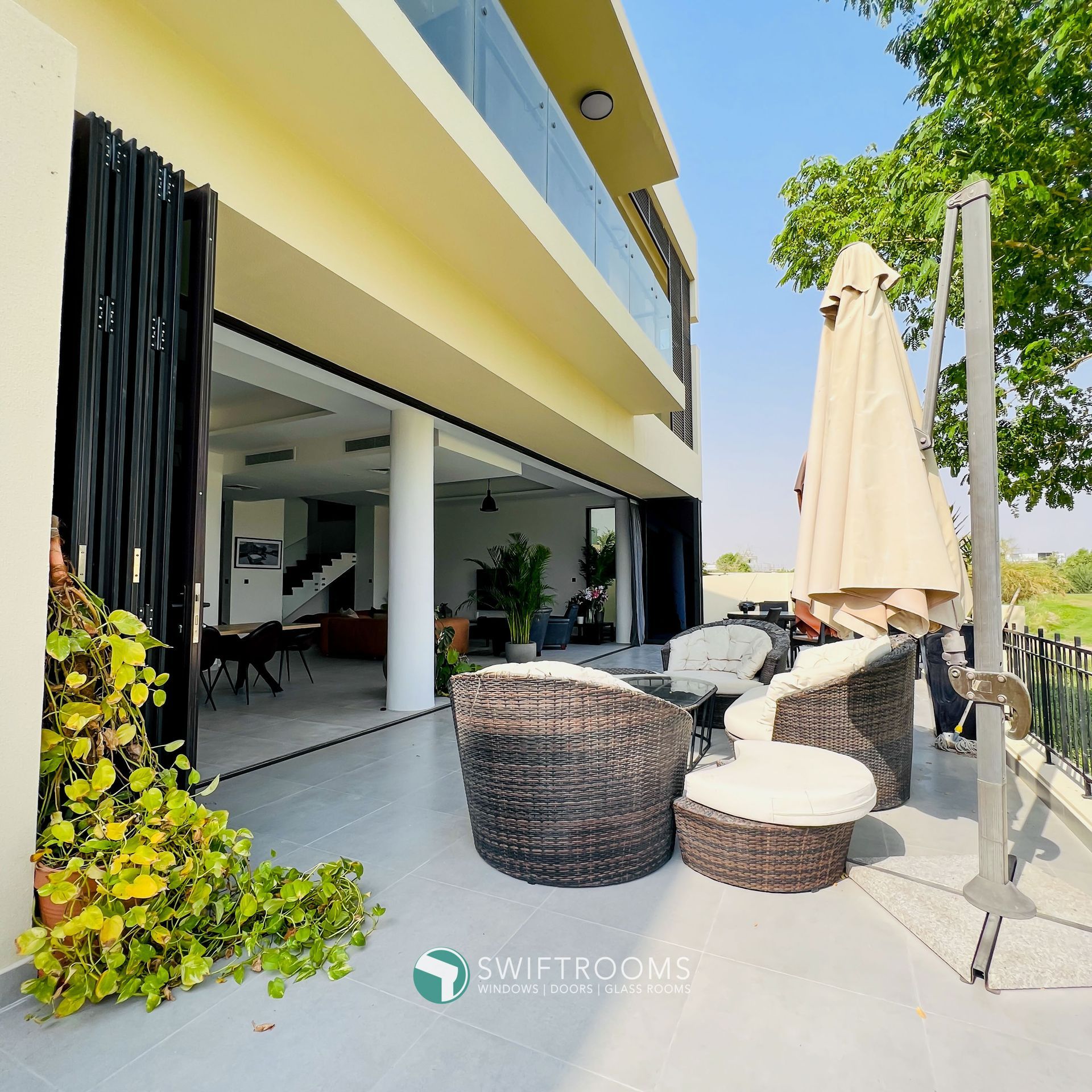 A balcony with wicker furniture and an umbrella with the word rooms on it