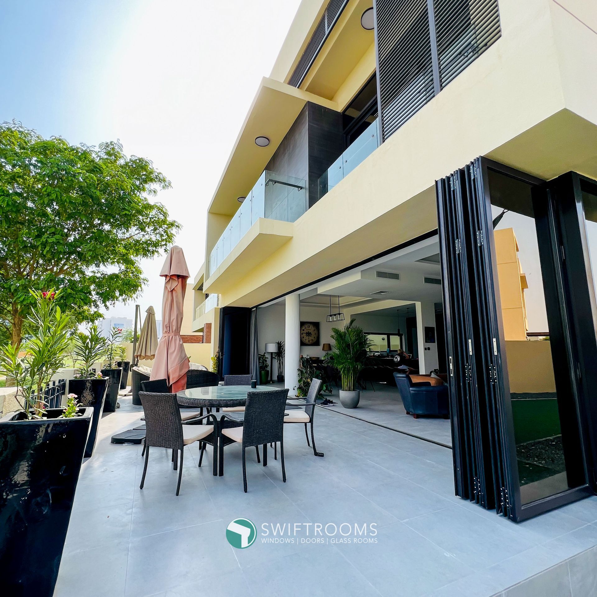 A large house with a patio with tables chairs and umbrellas