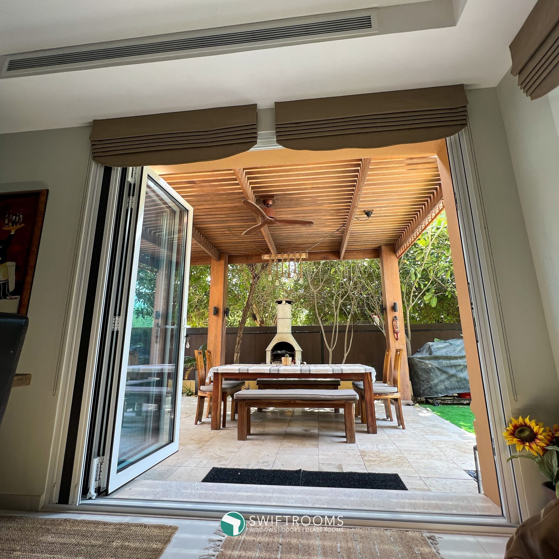 A patio with a table and benches under a pergola.