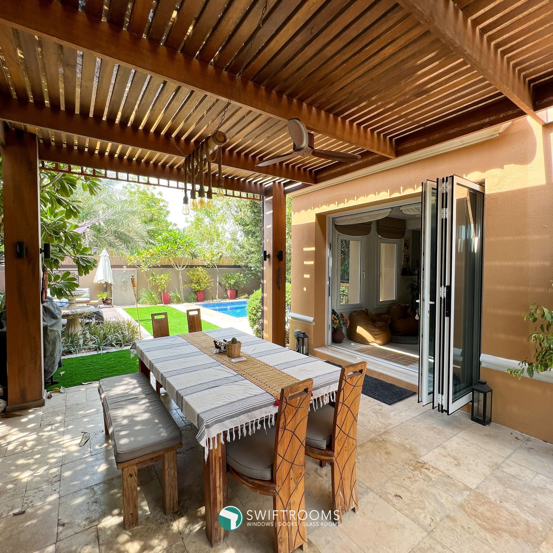 A patio with a table and chairs under a wooden pergola