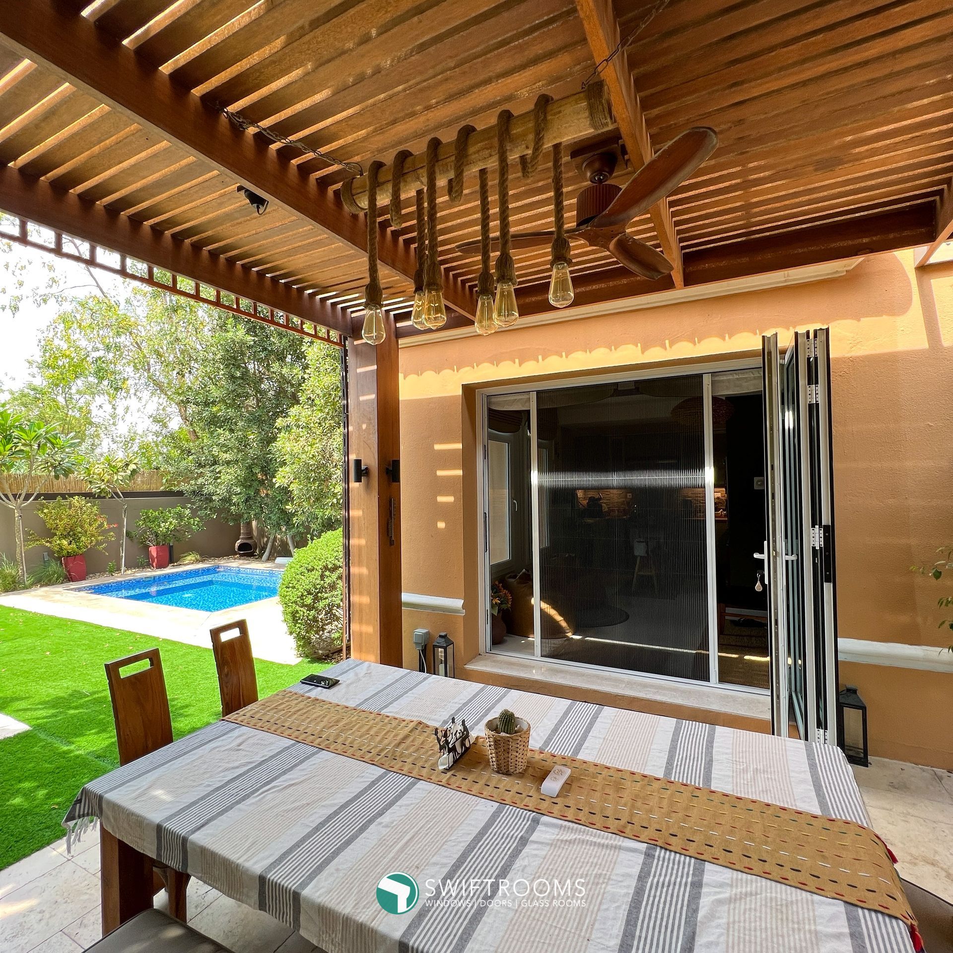 A patio with a table and chairs and a pool in the background