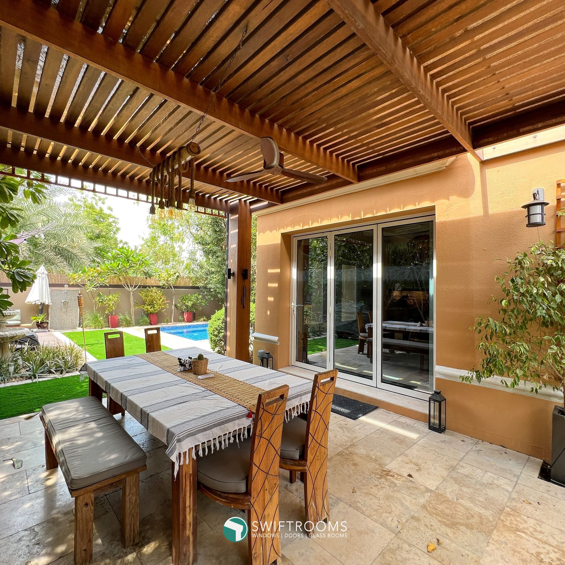 A patio with a table and chairs under a wooden pergola