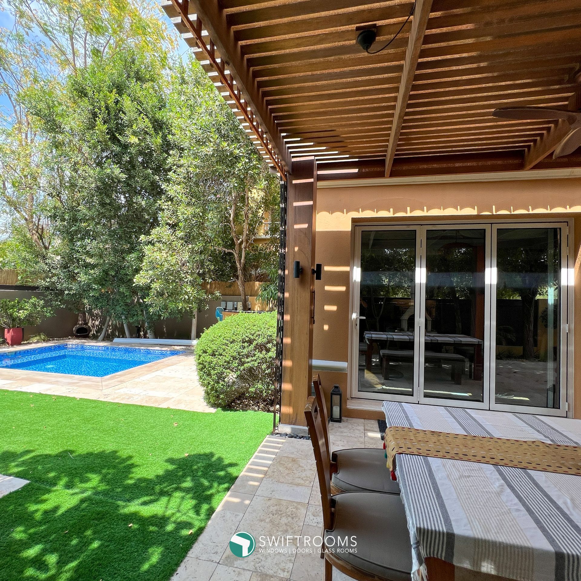 A patio with a table and chairs and a pool in the background