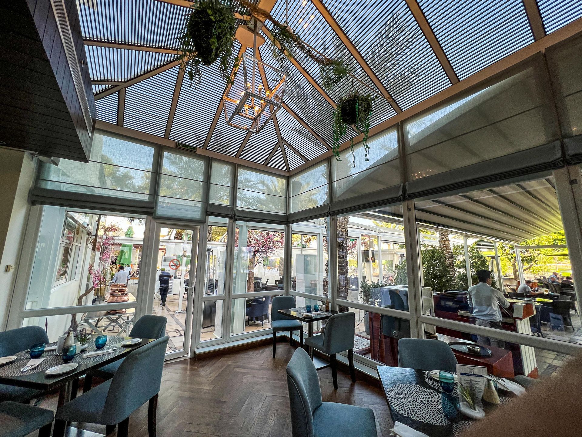 A restaurant with tables and chairs and a large glass ceiling.