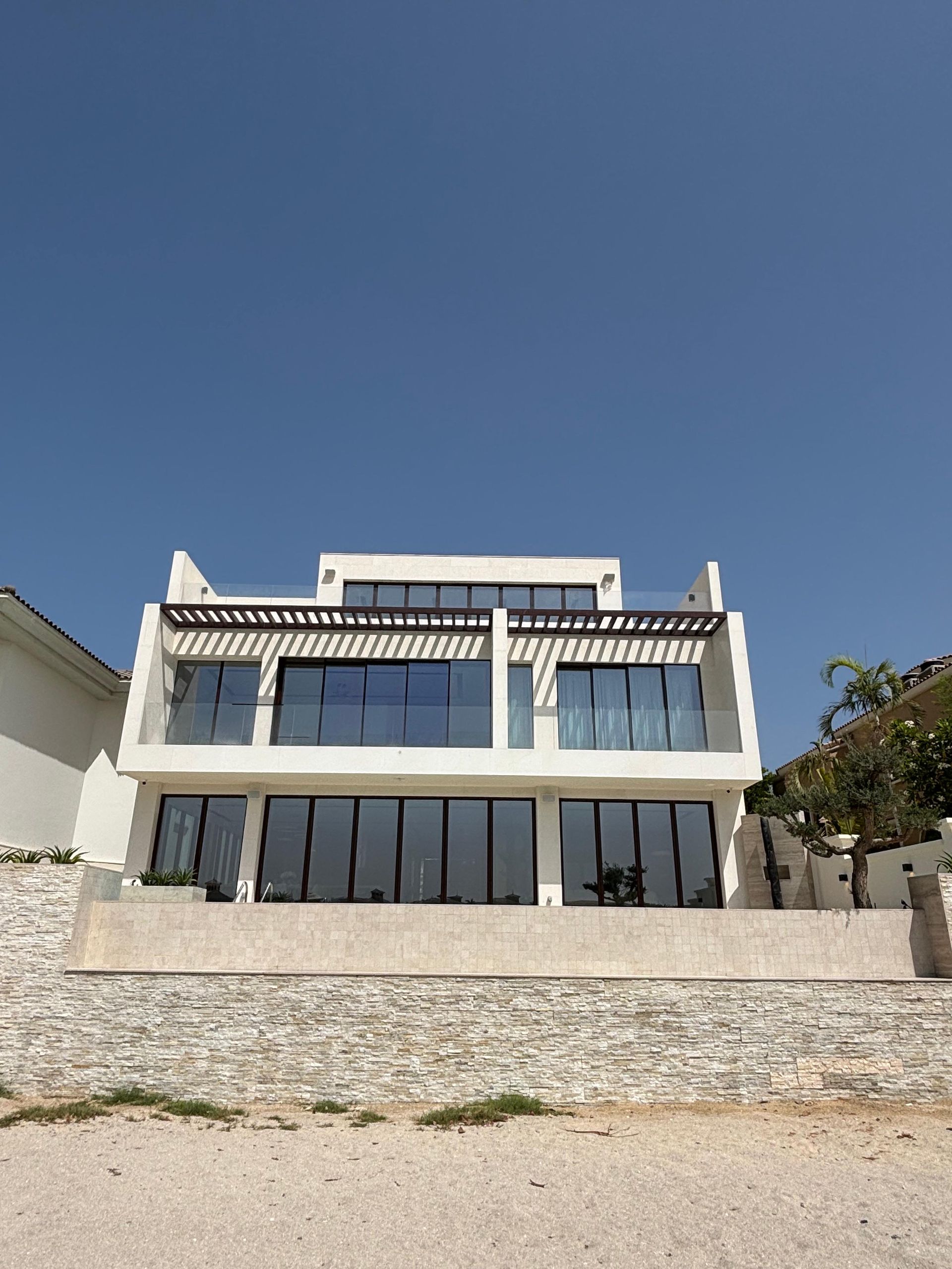 A large white house with a lot of windows is sitting on top of a hill.