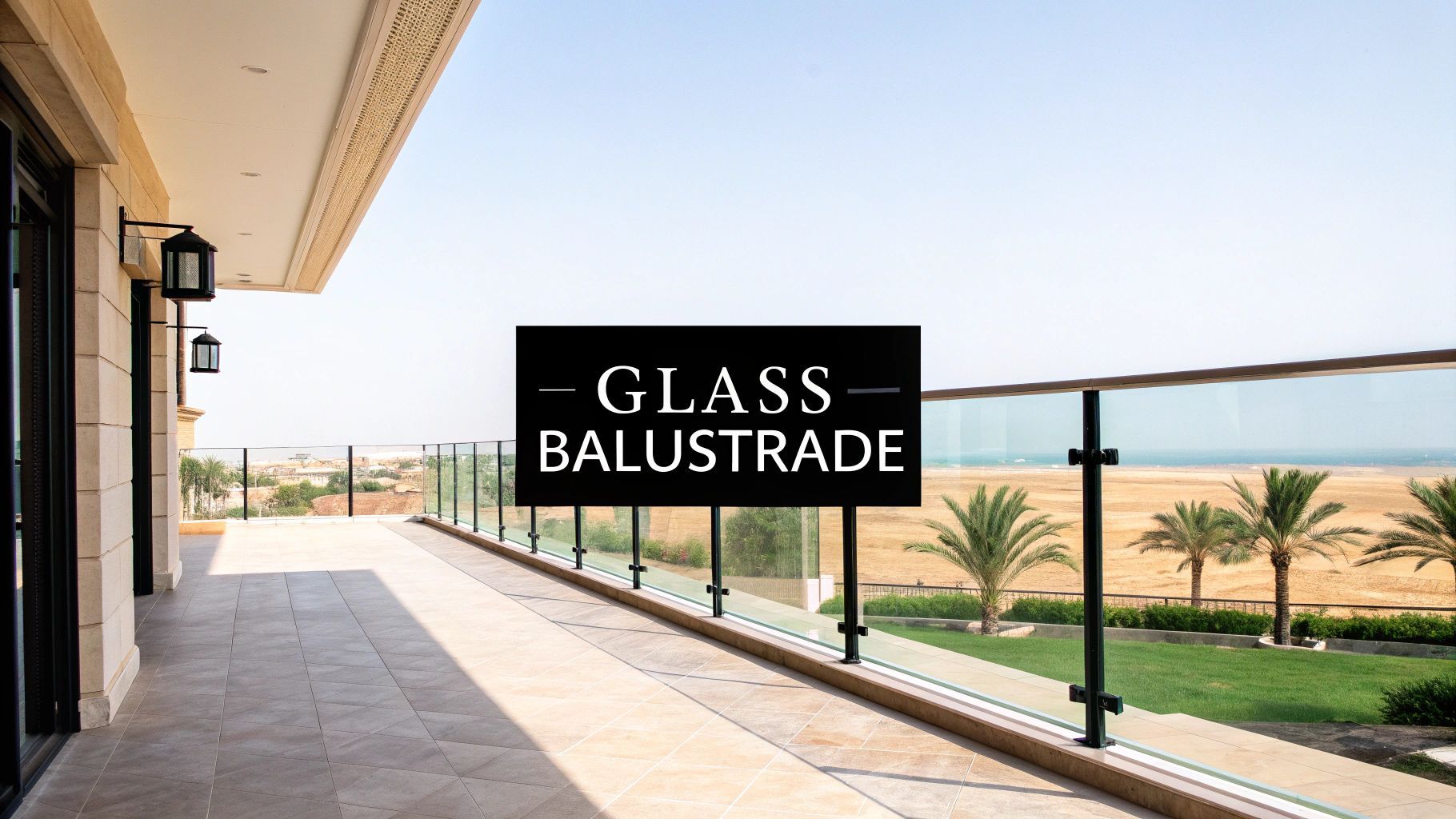 Balcony with glass balustrade overlooking a beach and palm trees.