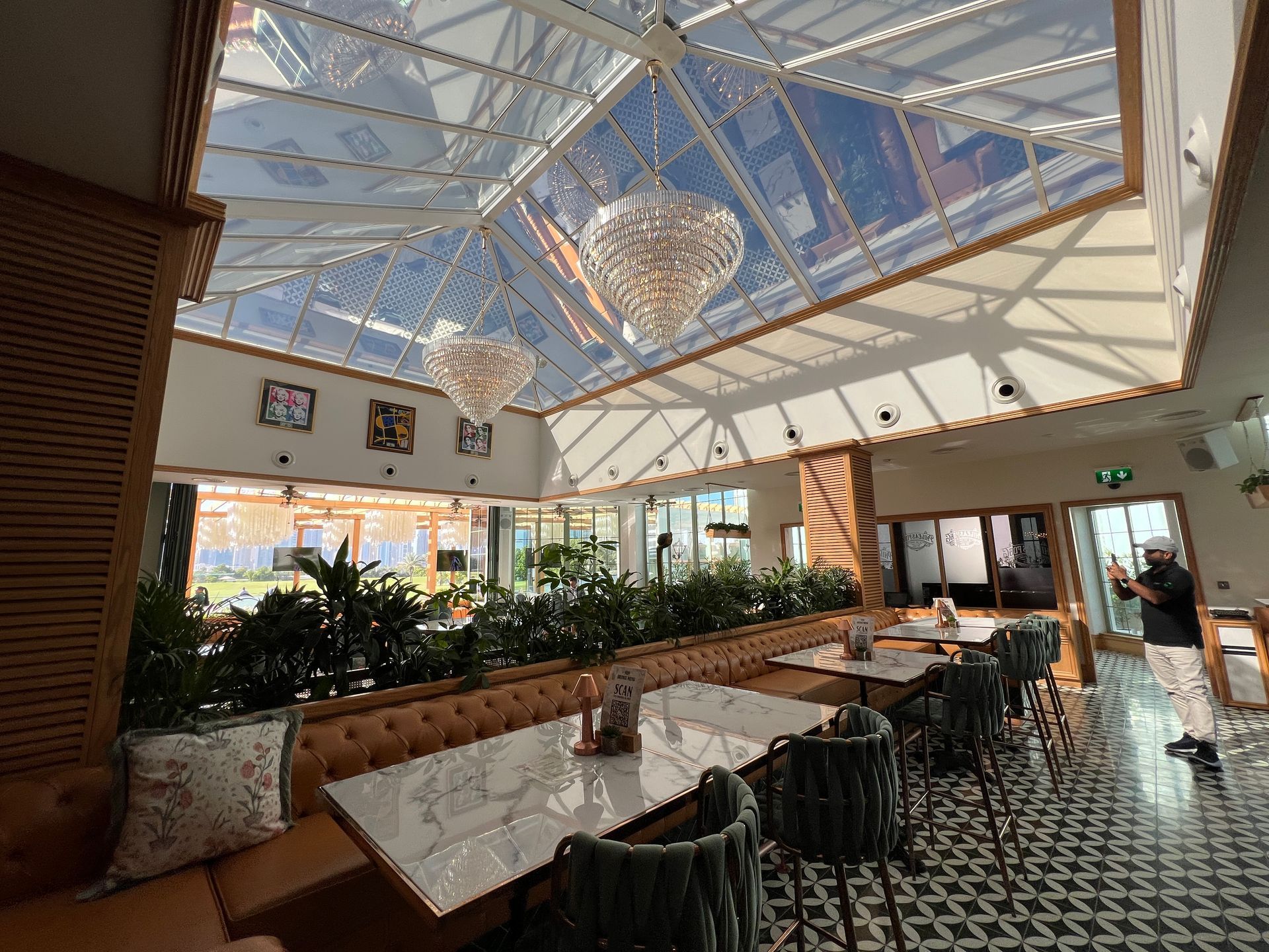 A restaurant with tables and chairs and a glass ceiling.