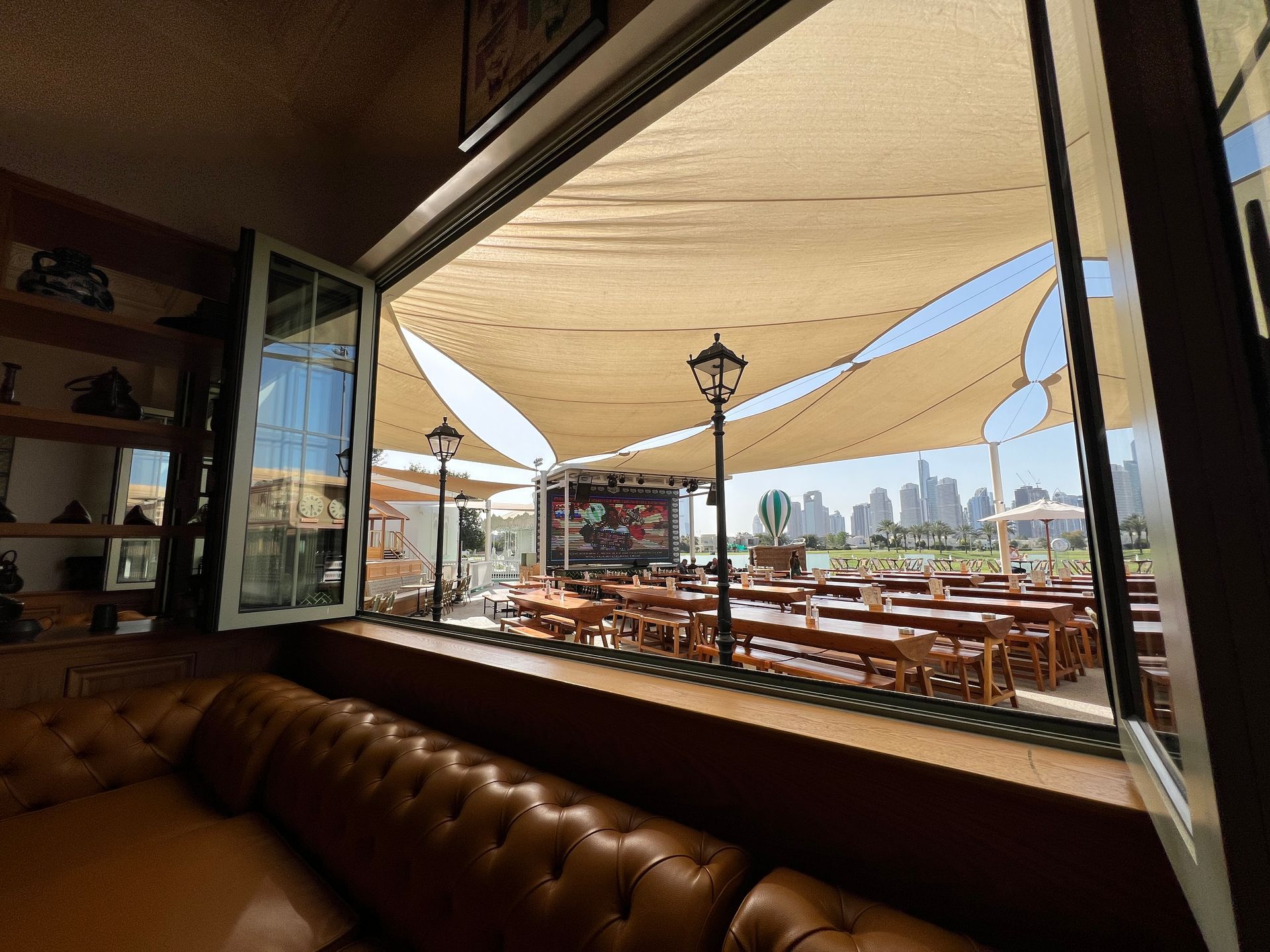 A view of a restaurant with tables and umbrellas from a window.
