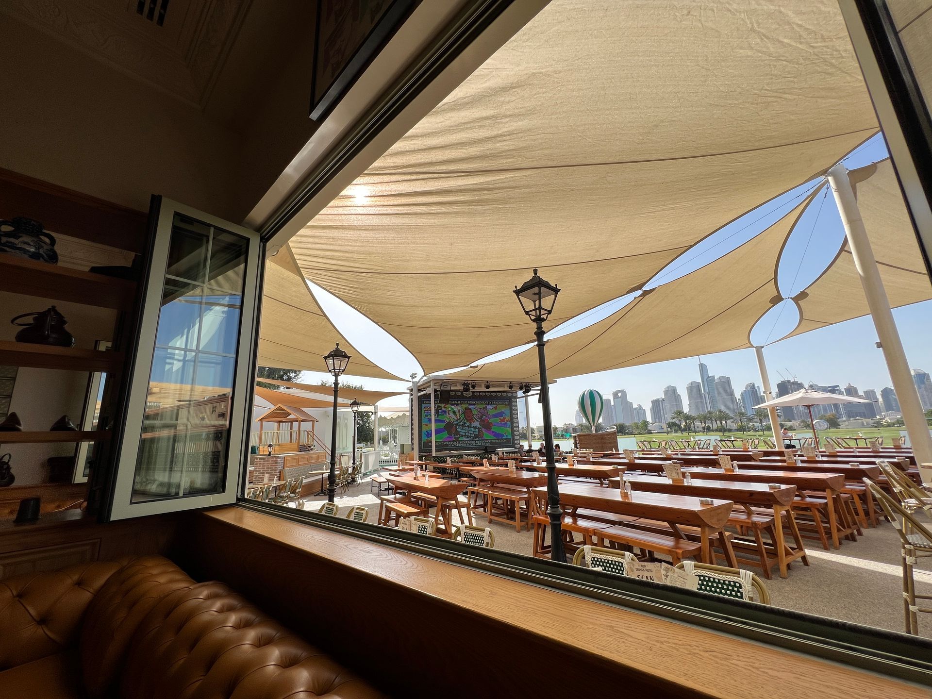 A view of a restaurant with tables and umbrellas from a window.