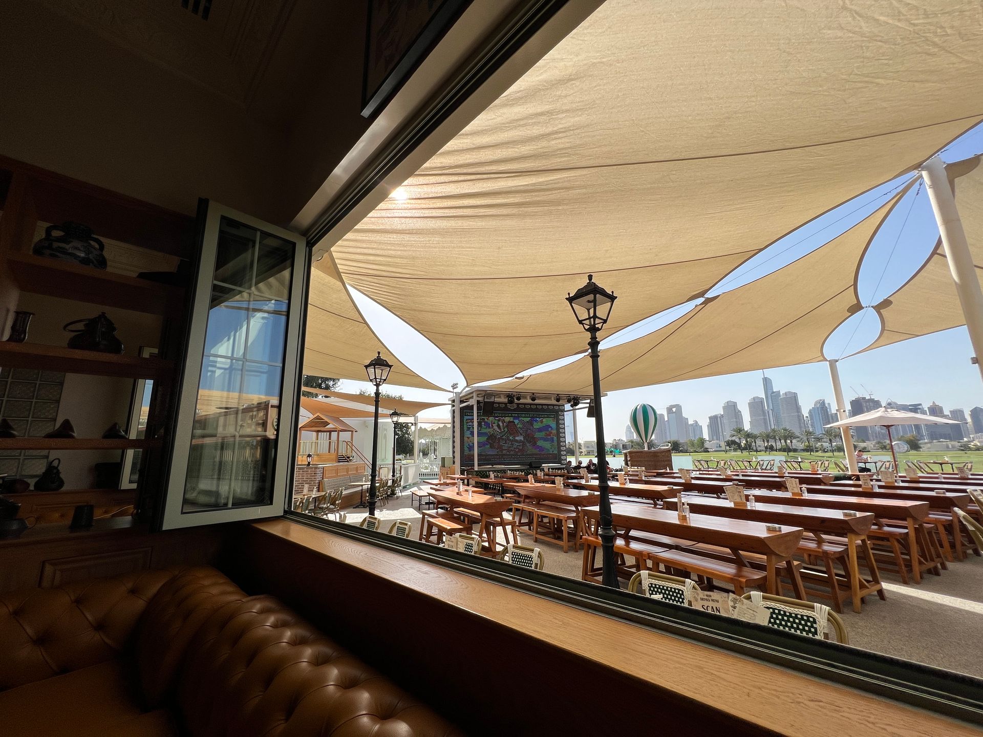 A restaurant with tables and chairs under umbrellas and a view of the city.