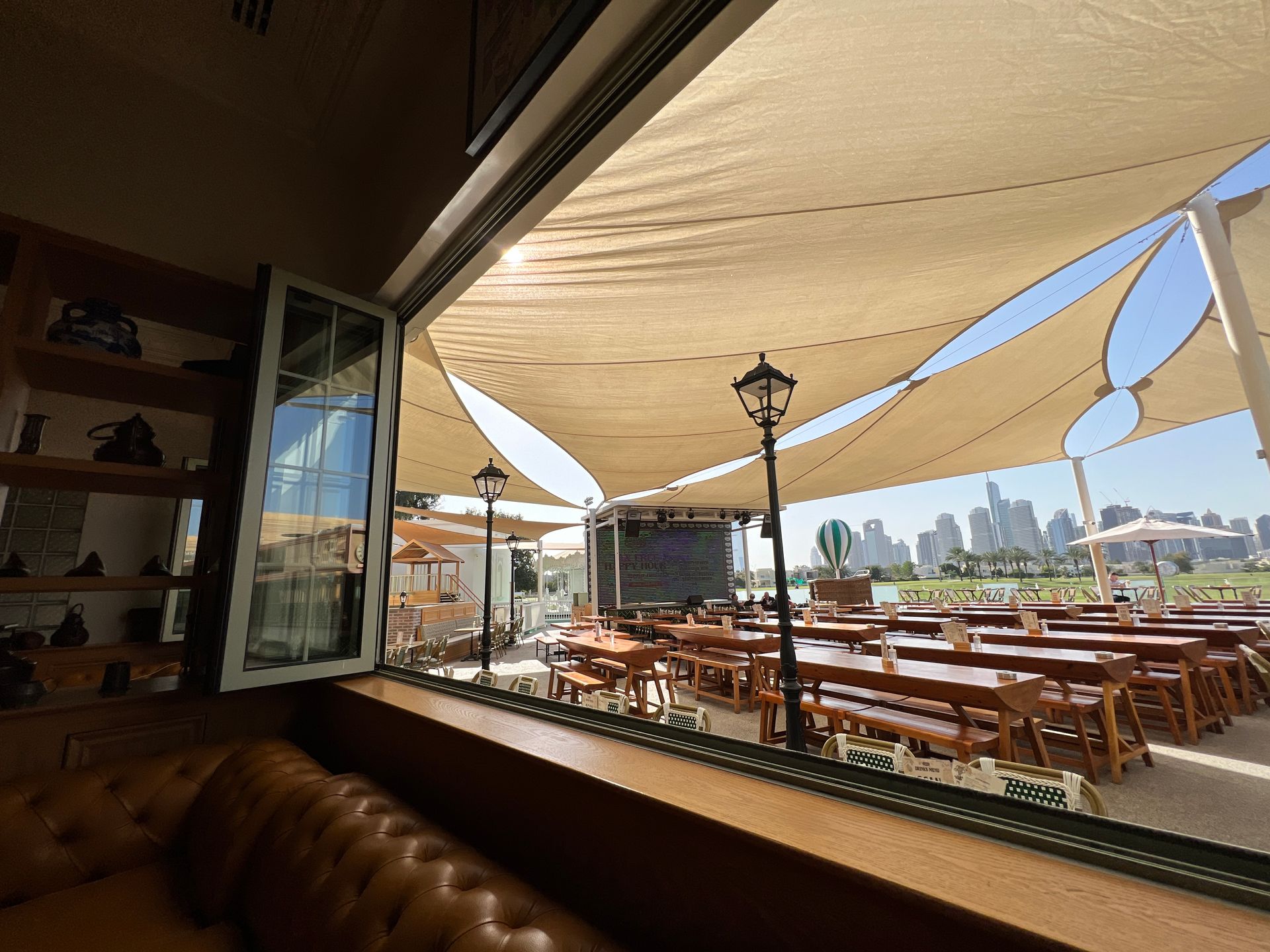A view of a restaurant with tables and umbrellas from a window.