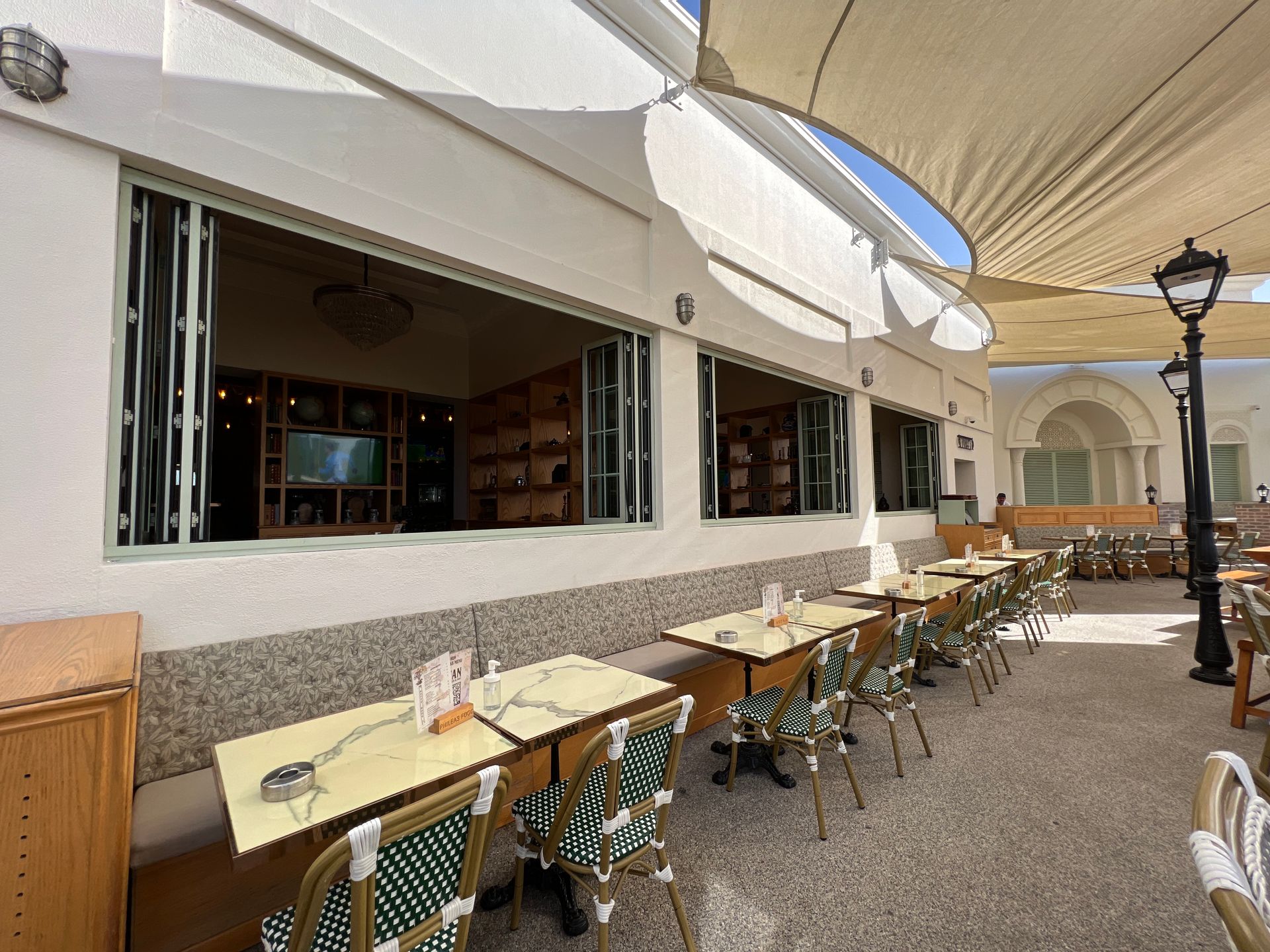A restaurant with tables and chairs outside with umbrellas.