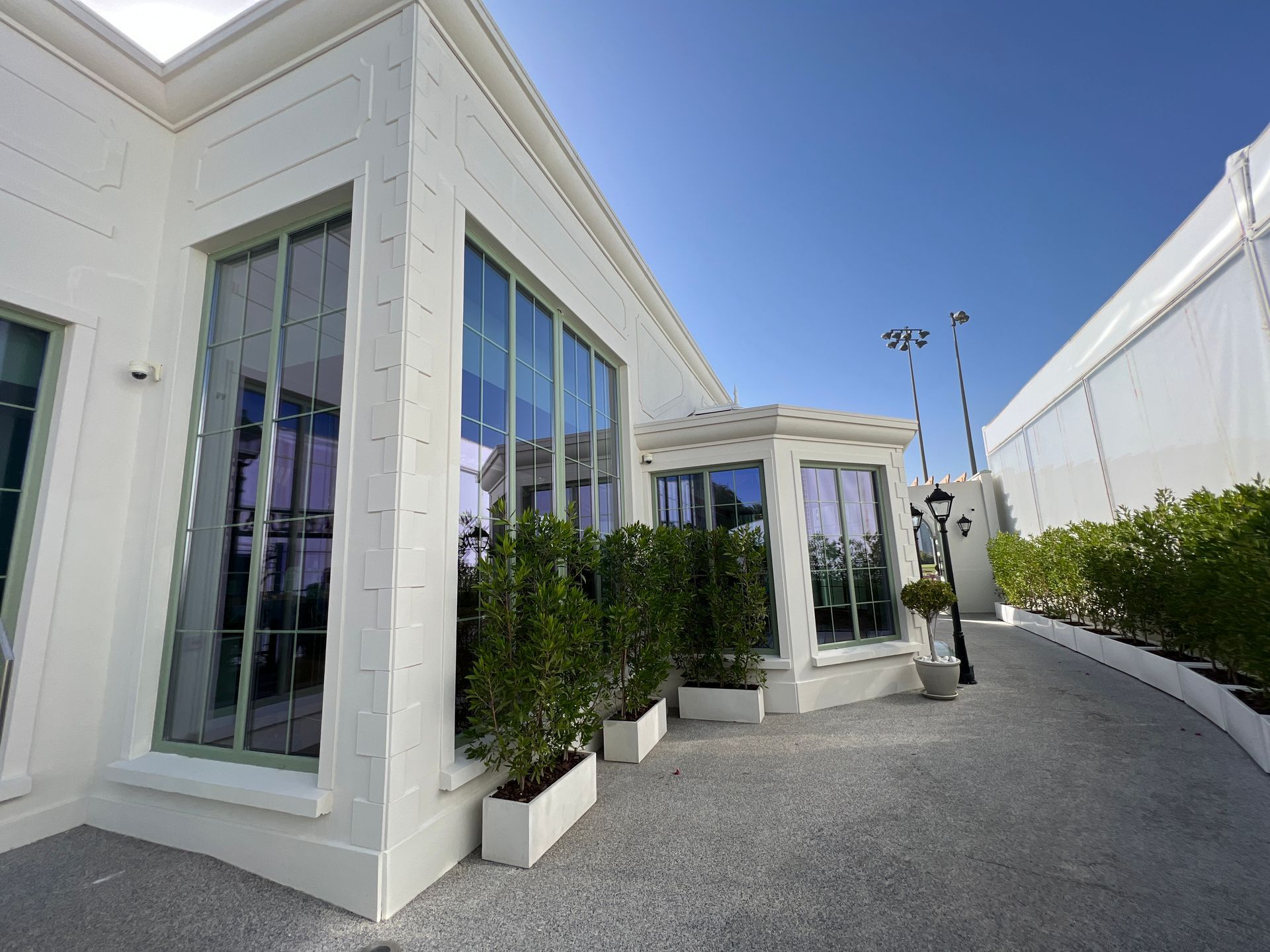 A white building with a lot of windows and plants in front of it