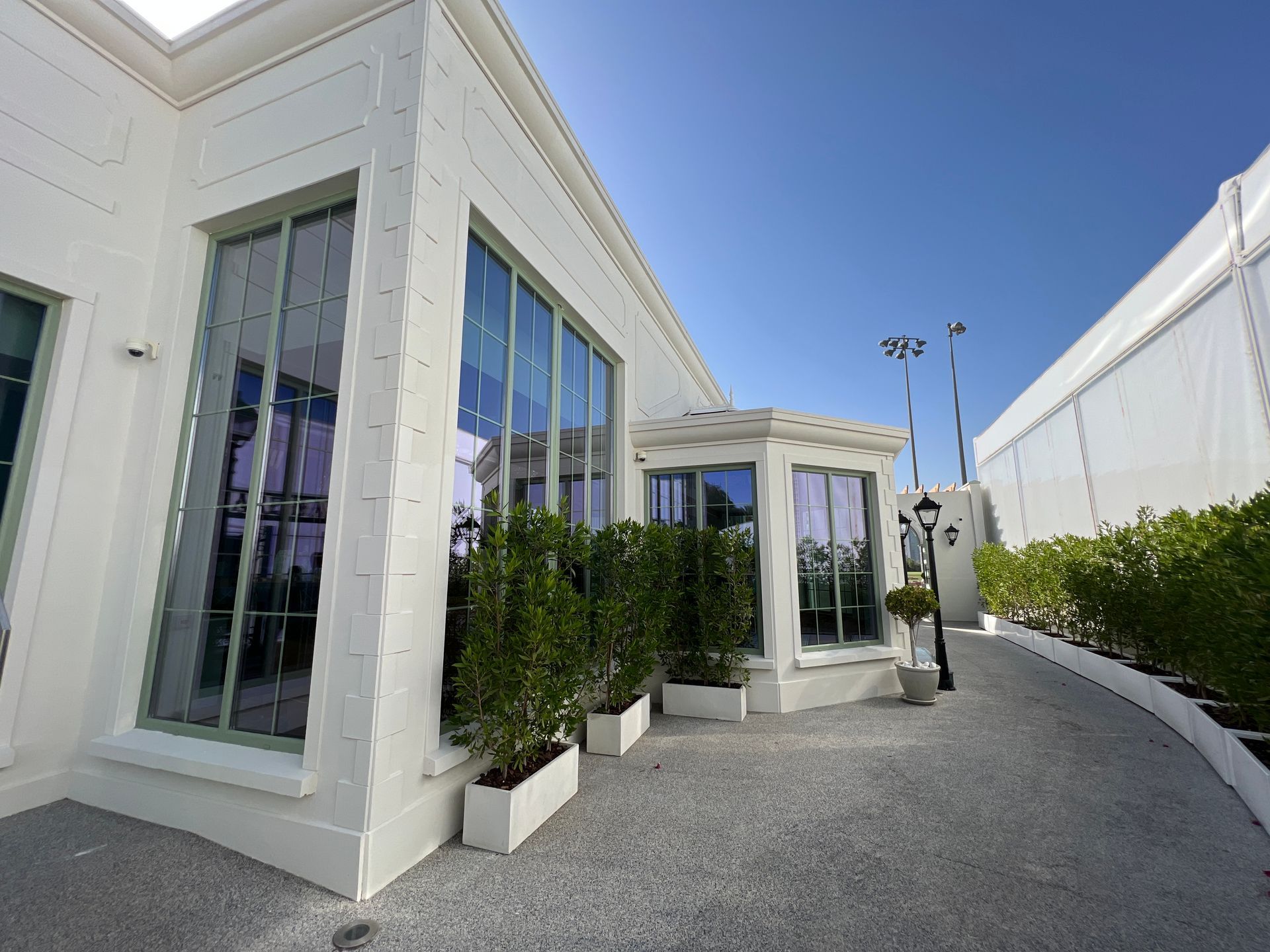 A white building with a lot of windows and plants in front of it
