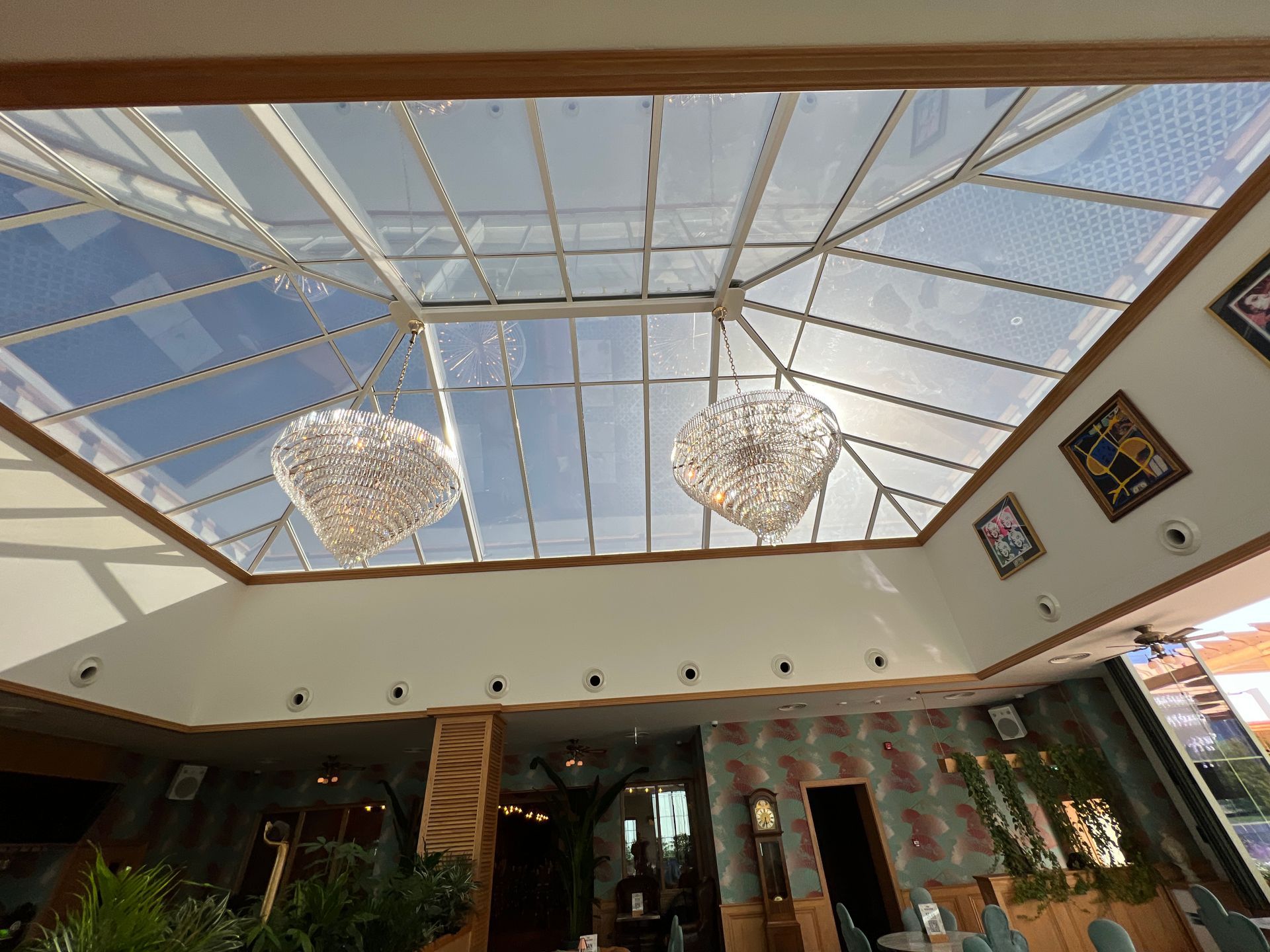 A room with a glass ceiling and two chandeliers hanging from it.
