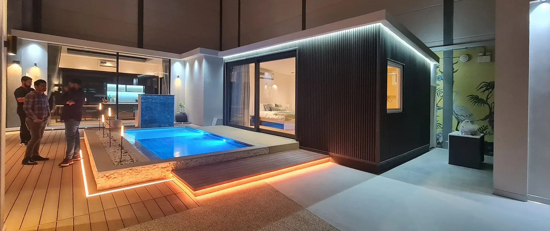 A group of people are standing in front of a house with a swimming pool.