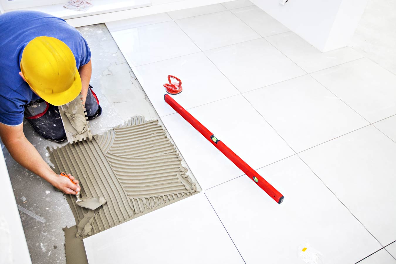 Man Laying large White Tiles — Home Renovations in Port Macquarie, NSW