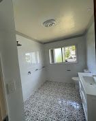 A bathroom with a sink , toilet , shower and window.