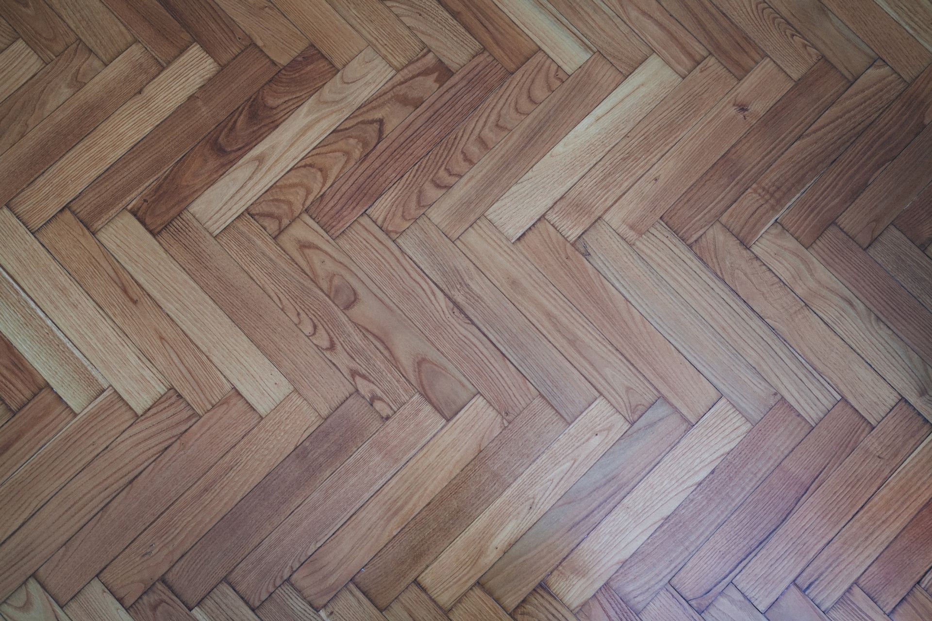 Herringbone pattern wooden floor in various shades of brown.