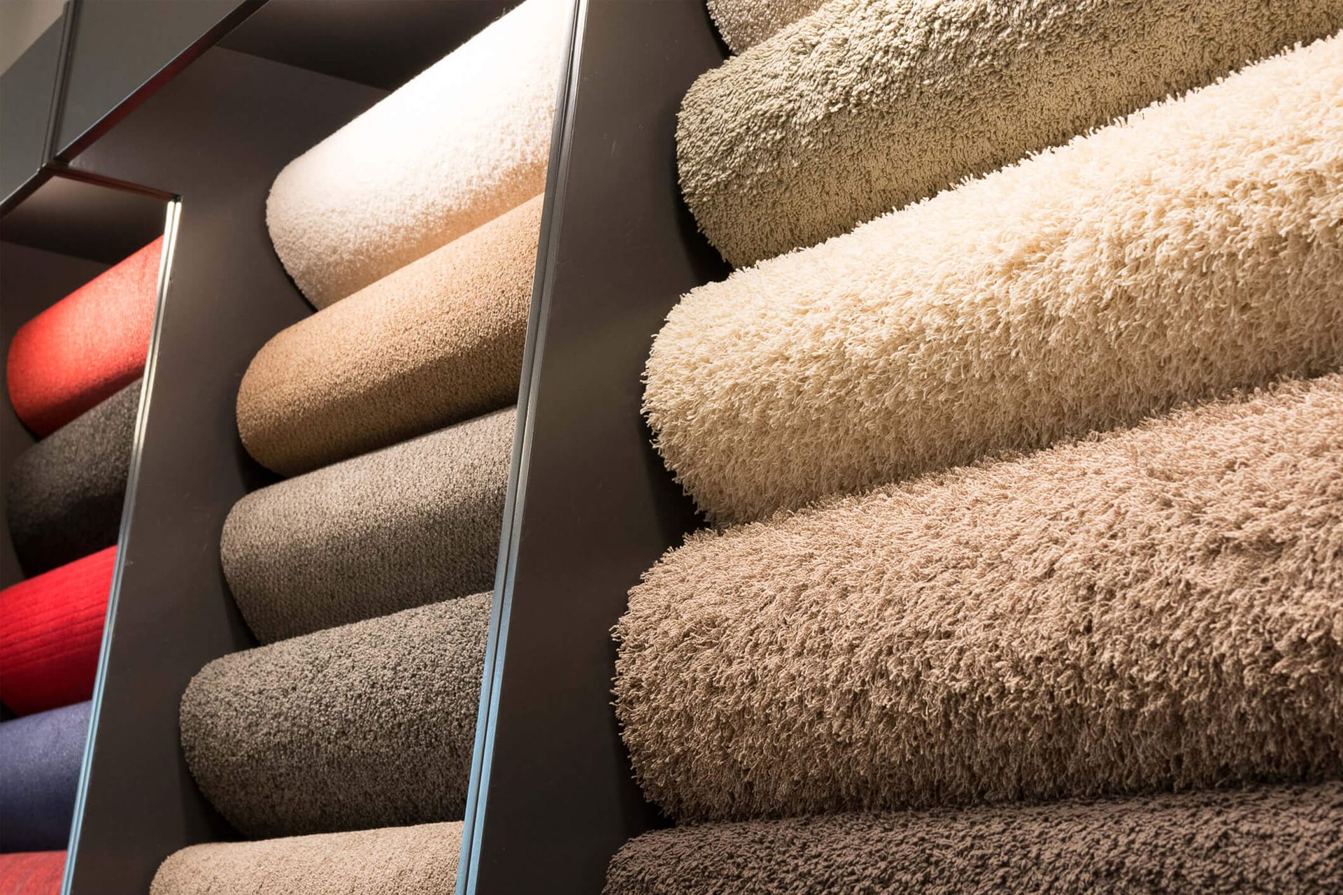 Carpet samples rolled up and arranged on shelves, in various neutral colors.