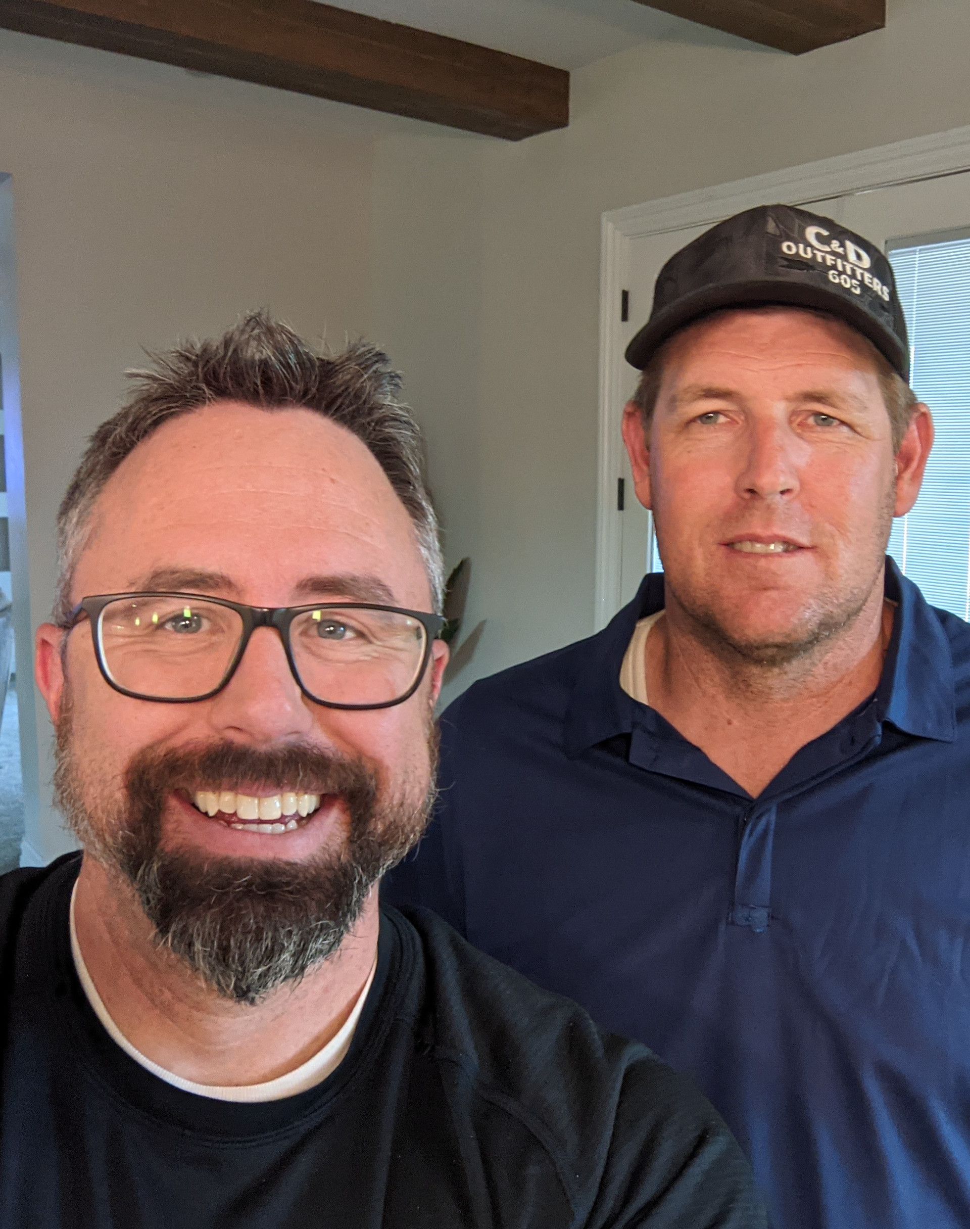 A man with glasses and a beard is standing next to another man