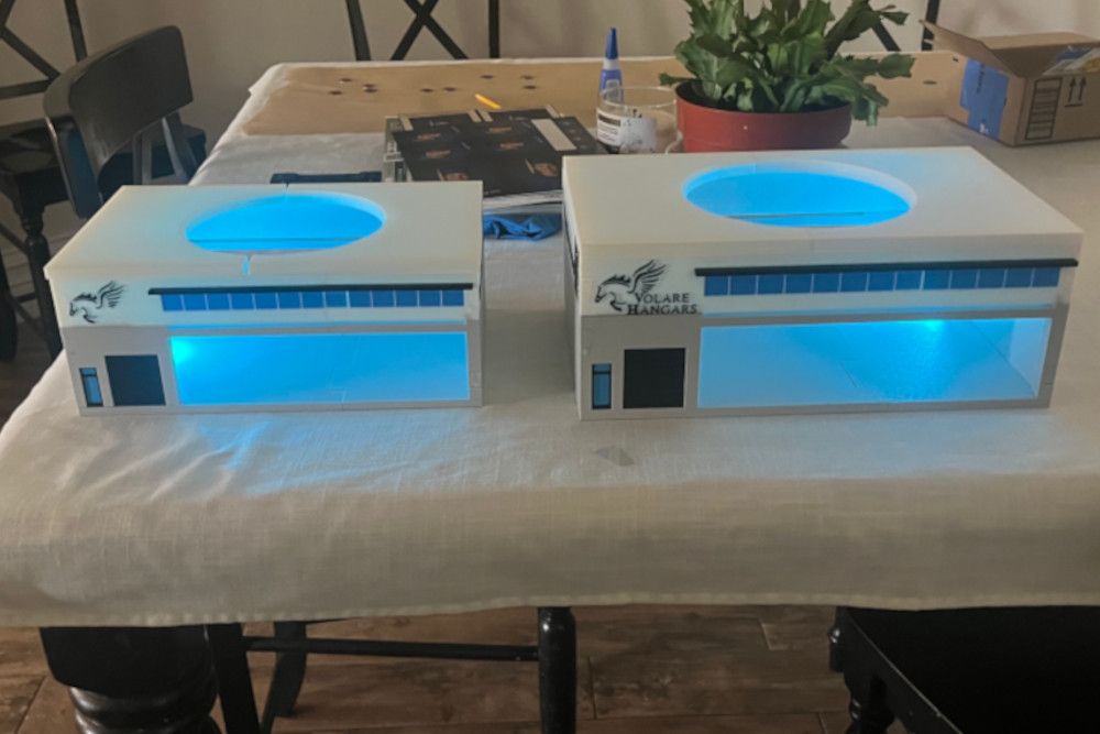 Two model houses on a table with blue lights on them