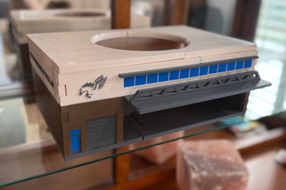 A model of a building is sitting on a glass shelf.