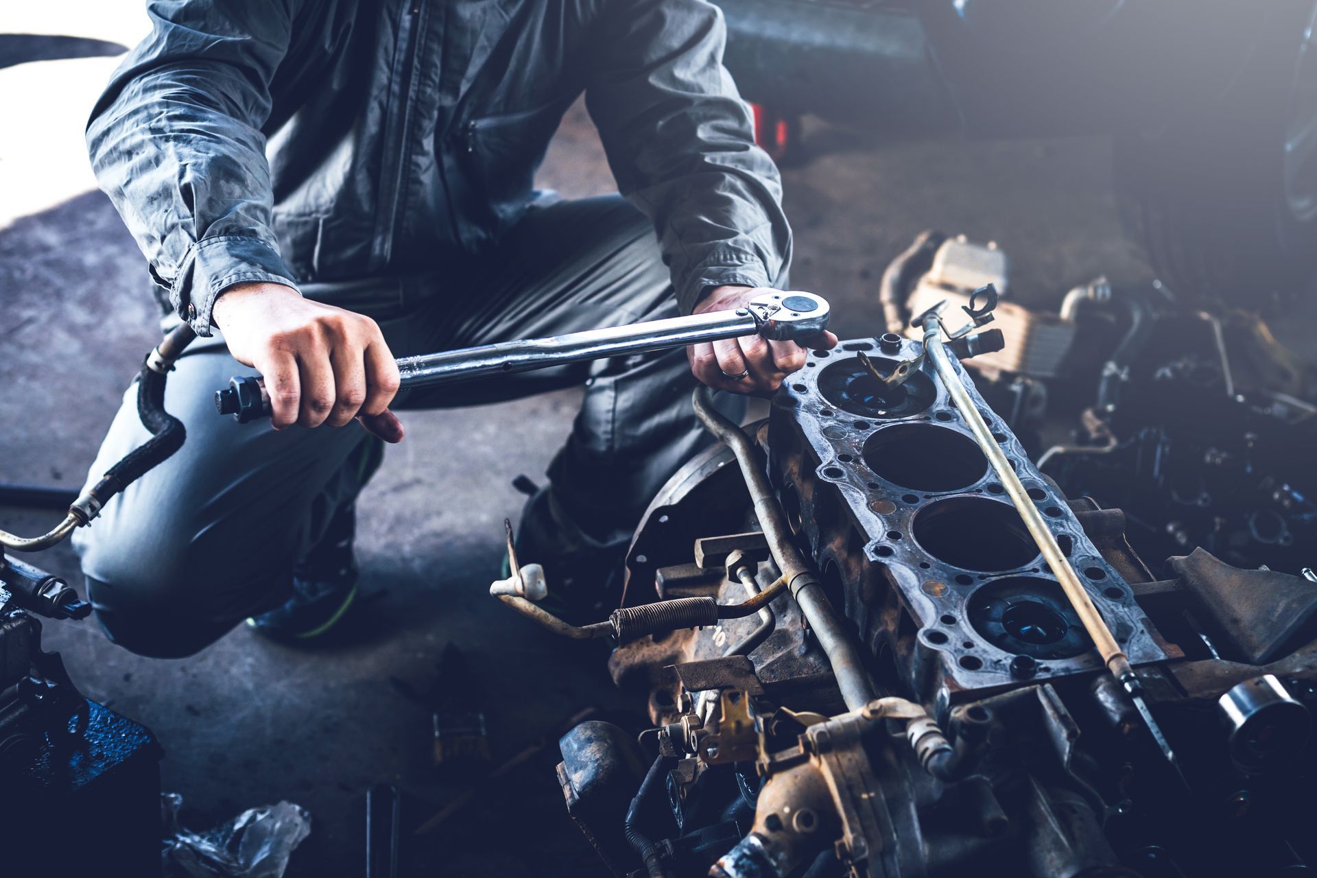 Mechanic working on an engine with a wrench in a garage.