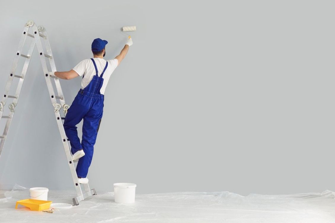 A man is standing on a ladder painting a wall.