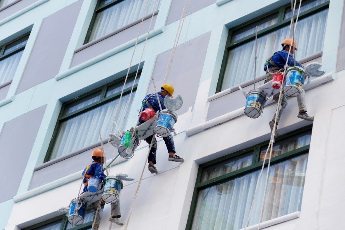A group of men are painting the side of a building.