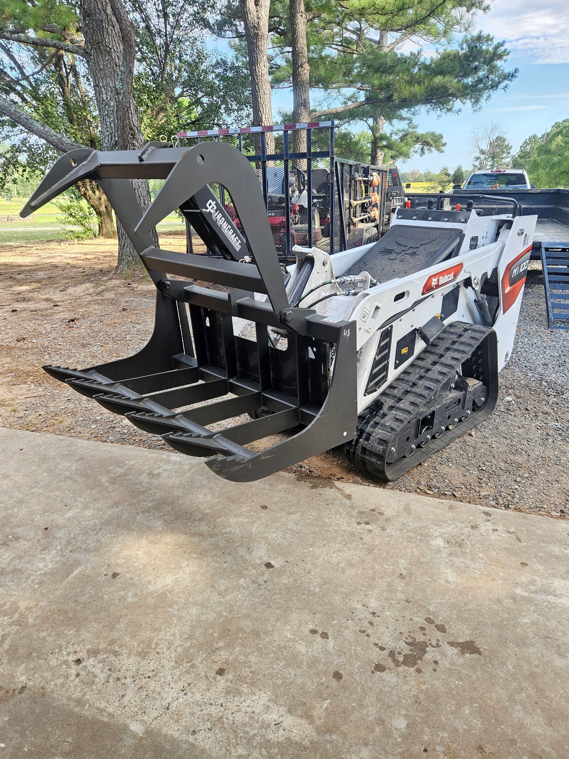 A bulldozer with a grapple attached to it is parked on the side of the road.