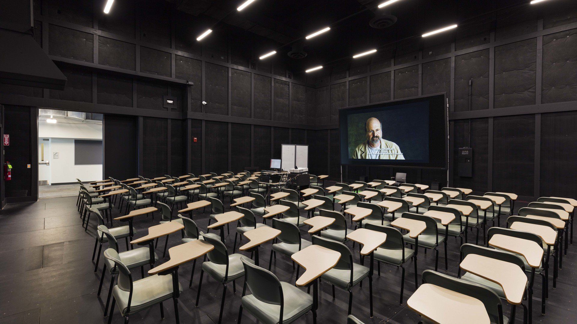 A large conference room with tables and chairs and a flat screen tv.