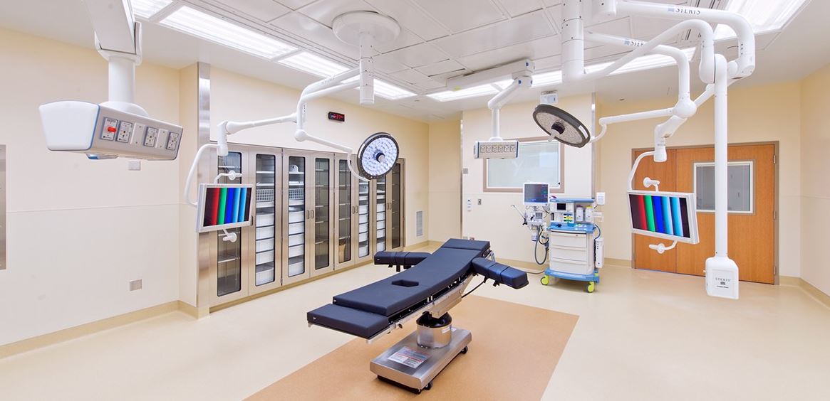 An empty operating room with an operating table and surgical equipment.