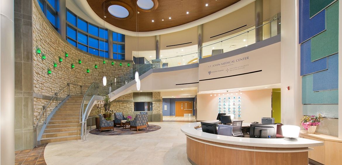 A large lobby with a staircase and a reception desk in a hospital.