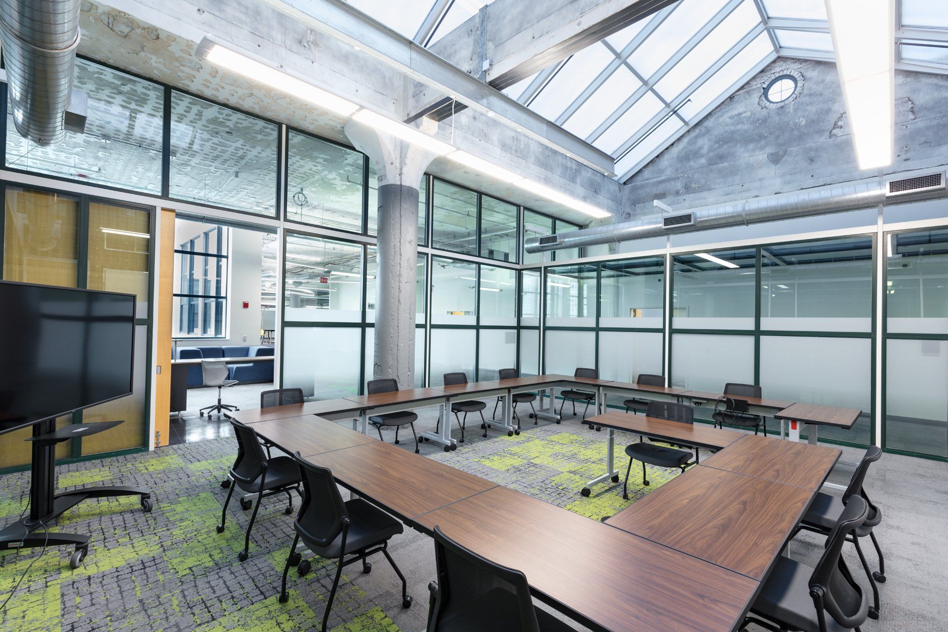 A large conference room with tables and chairs and a flat screen tv.